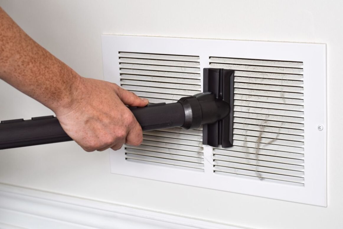 furnace duct cleaning vent using vacuum cleaner white wall inside house